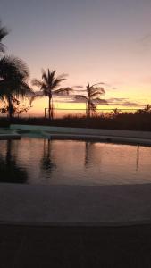 a pool of water with palm trees at sunset at PH OLAS TOWERS FRONT. PLAYA LA BARQUETA in Chiriquí