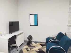 a living room with a tv and blue chairs at Apartamentos aconchegantes no centro da cidade in Cacoal