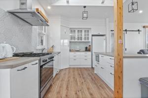 een keuken met witte kasten en een houten vloer bij SALTAIR Beach House Right in Town in Portland
