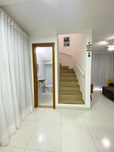 a living room with a staircase and white curtains at Linda casa beira da praia in Lauro de Freitas