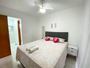 Linda casa beira da praia في لورو دي فريتاس: غرفة نوم مع سرير كبير مع وسادتين ورديتين