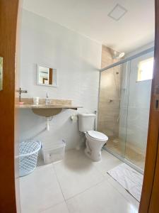 a white bathroom with a toilet and a shower at Linda casa beira da praia in Lauro de Freitas