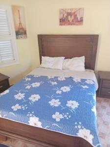 Una cama con una colcha azul con flores blancas. en Hotel V. Maria, en Eslabón