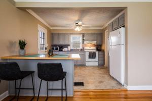 a kitchen with a white refrigerator and two bar stools at Colonial Village Retreat 2BR in New Albany