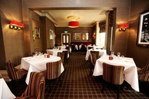 a dining room with tables and chairs with white table cloth at Belmont Hotel Leicester in Leicester