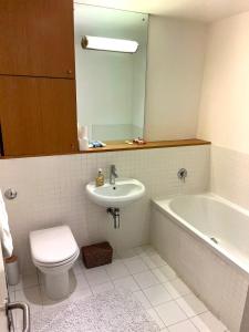 a bathroom with a sink and a tub and a toilet at Spacious Queen Bed City Centre Penthouse With Balcony - Homeshare - Live In Host in Glasgow