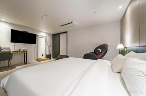 a bedroom with a large white bed with two chairs at gray195hotel in Gimhae