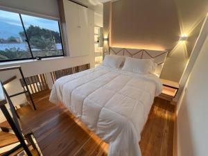 um quarto com uma cama branca e uma grande janela em 'SELECT' Medellin em Medellín