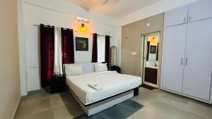 Western Ghats Holiday Home في كالباتّا: غرفة نوم بسرير ابيض في غرفة