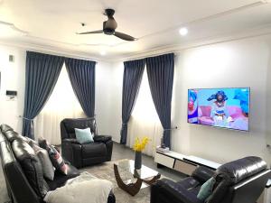 sala de estar con muebles de cuero negro y TV de pantalla plana en Ayan Villas en Accra