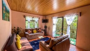 ein Wohnzimmer mit Ledermöbeln und großen Fenstern in der Unterkunft Casa Euphonia Monteverde in Monteverde Costa Rica