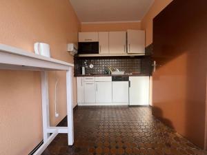 a small kitchen with white cabinets and a tile floor at Simplex Apartments An Der Dreisam in Freiburg im Breisgau