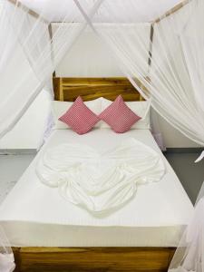 a bed with white sheets and pink pillows at Swiss kiss beach resort in Uppuveli