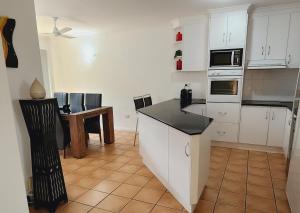 a kitchen with white cabinets and a black counter top at Beach Court Holiday Villas 4n each guest get free Day trip Kens Klassic Kombi in Airlie Beach