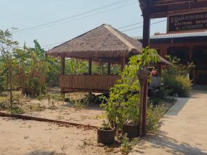 a pavilion with a straw roof in front of a building at Melop Koki Homestay 7 in Krong Kracheh