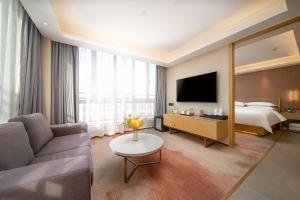 um quarto de hotel com um sofá, uma cama e um espelho em Guangzhou Baiyun Airport Yunzhi Hotel near Terminal One em Guangzhou
