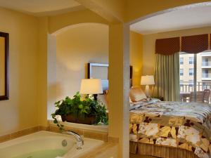 Be Our Guest في أورلاندو: غرفة نوم مع سرير وحوض استحمام بجانب سرير