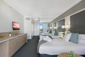 a hotel room with three beds and a television at Cosy 2-Bed Central Studio Apartment With Views in Gold Coast