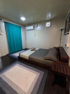 a bedroom with a bed and a blue curtain and a rug at Seahorse Diver Guesthouse in Perhentian Island