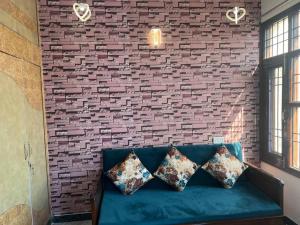 a brick wall with a blue couch with pillows at Authentic Indian Culture in Panchkula