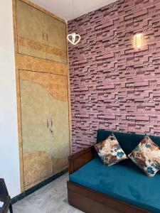 a room with a blue couch and a brick wall at Authentic Indian Culture in Panchkula