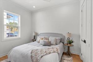 a white bedroom with a bed and a window at Chandeleur Town Home in Pass Christian