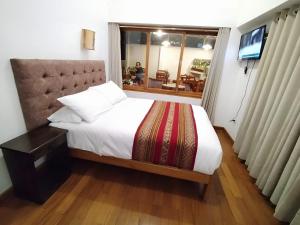 1 dormitorio con cama, ventana y TV en Paqarina San Blas, en Cusco