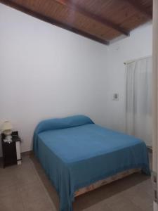 une chambre avec un lit bleu dans une pièce blanche dans l'établissement Casa cerca del centro con cochera, à Posadas