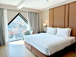 a large bed in a hotel room with a large window at Ramada by Wyndham Bangkok Sukhumvit 11 in Bangkok