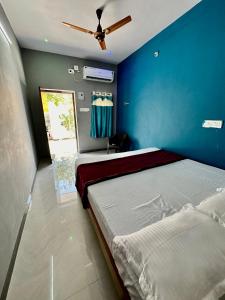 1 dormitorio con 2 camas y pared azul en Arunachala Sashwin Guest House en Tiruvannāmalai