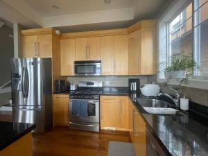 a kitchen with wooden cabinets and a stainless steel refrigerator at Guest room in Langford in Victoria