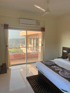 a bedroom with a large window with a view at Hotel Mahabaleshwar Mount View in Mahabaleshwar