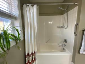 a bathroom with a tub and a shower curtain at Guest room in Langford in Victoria