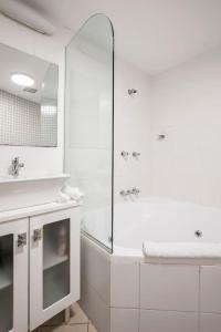 a white bathroom with a shower and a sink at The Earl - Potts Point Paradise with Sydney Views in Sydney