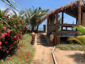 a building with a bench and flowers on the beach at Bela casa de praia beira mar in Feliz Deserto