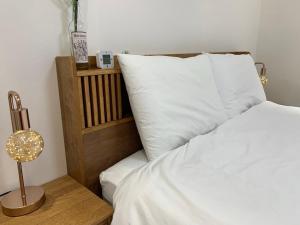 a bed with a white pillow and a nightstand with a lamp at Comma 2, Cozy Semi-basement in Seoul