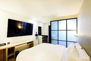 a bedroom with a white bed and a large tv at CS Avenue Tourist Hotel in Seoul