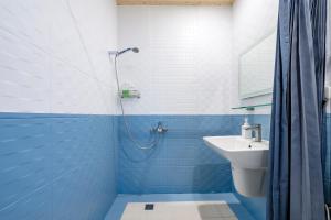 uma casa de banho azul e branca com um lavatório e um chuveiro em Cozy Blue B&B em Taitung City
