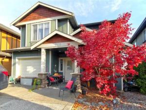 a house with a red tree in front of it at Guest room in Langford in Victoria