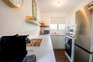 a kitchen with a refrigerator and a counter top at Cosy Straddie cottage + sleeps 6 + close to beach in Point Lookout +3 photos