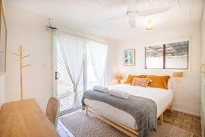 a bedroom with a large bed and a table at Cosy Straddie cottage + sleeps 6 + close to beach in Point Lookout