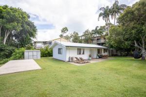 a small white house with a large yard at Cosy Straddie cottage + sleeps 6 + close to beach in Point Lookout