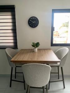 a dining room table with chairs and a clock on the wall at Cómodo Loft Tequis. Facturamos in San Luis Potosí