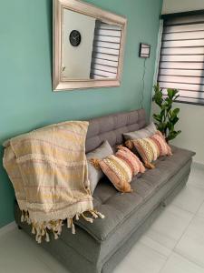 Sofá gris con almohadas en una habitación con espejo en Cómodo Loft Tequis. Facturamos, en San Luis Potosí