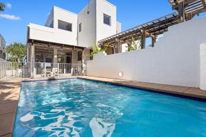 a swimming pool in front of a house at Saltwater Beach House in Yaroomba