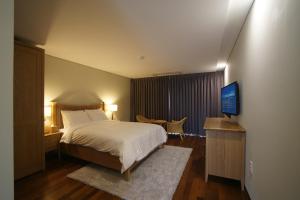 a bedroom with a bed and a flat screen tv at IlleInn Hotel in Seogwipo