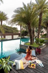 Eine Frau, die auf einer Picknickdecke neben einem Pool sitzt. in der Unterkunft Hyatt Centric MG Road Bangalore in Bangalore