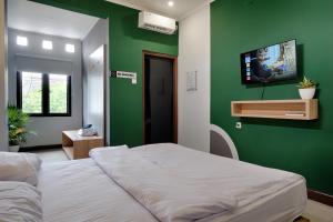 a bedroom with a bed and a green wall at HUBS Hostel Yogyakarta in Yogyakarta