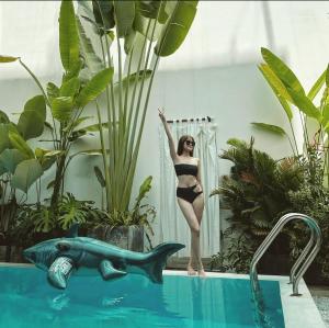 a woman in a bikini standing next to a blue shark next to a pool at LaDa's House in Da Nang