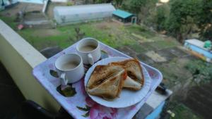 talerz tostów i dwie filiżanki kawy na stole w obiekcie Hotel Vardan - Ayur Stay w mieście Bijni